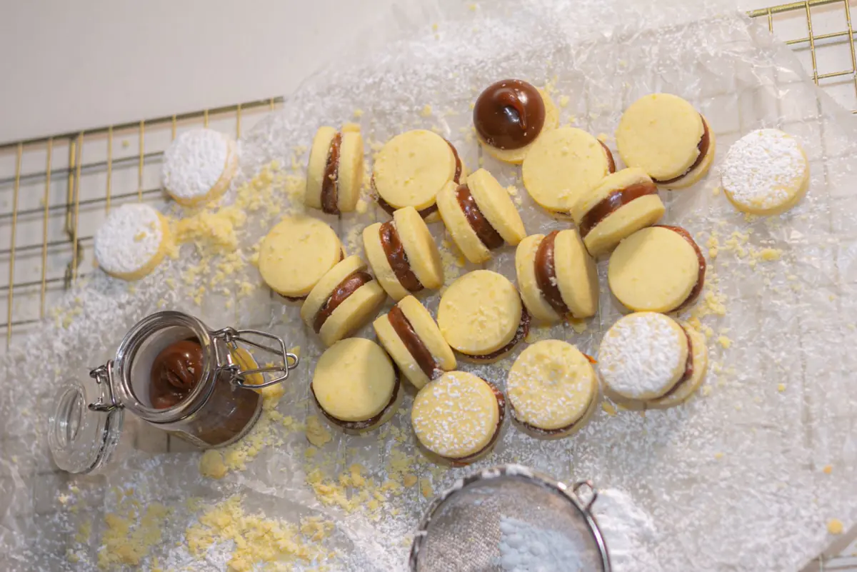 Alfajores rellenos de arequipe con azúcar pulverizada sobre una rejilla dorada