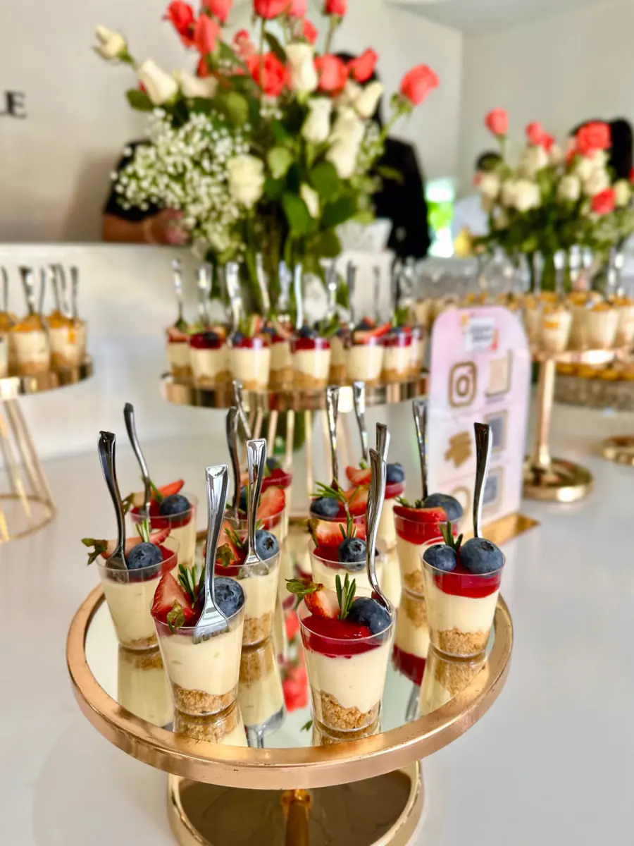 Mesa dulce de evento con postres en vaso, frutos rojos y arreglos de rosas